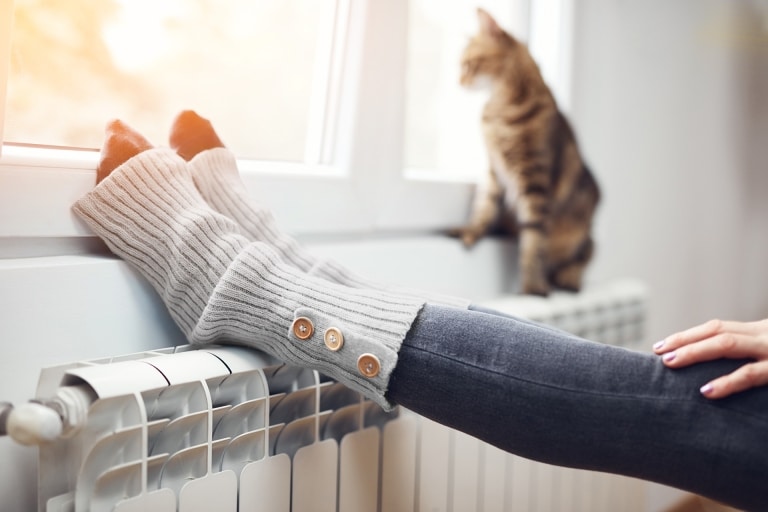 Füße auf Heizkörper mit Katze