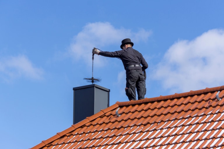 Rauchfangkehrer kehrt Kamin am Dach