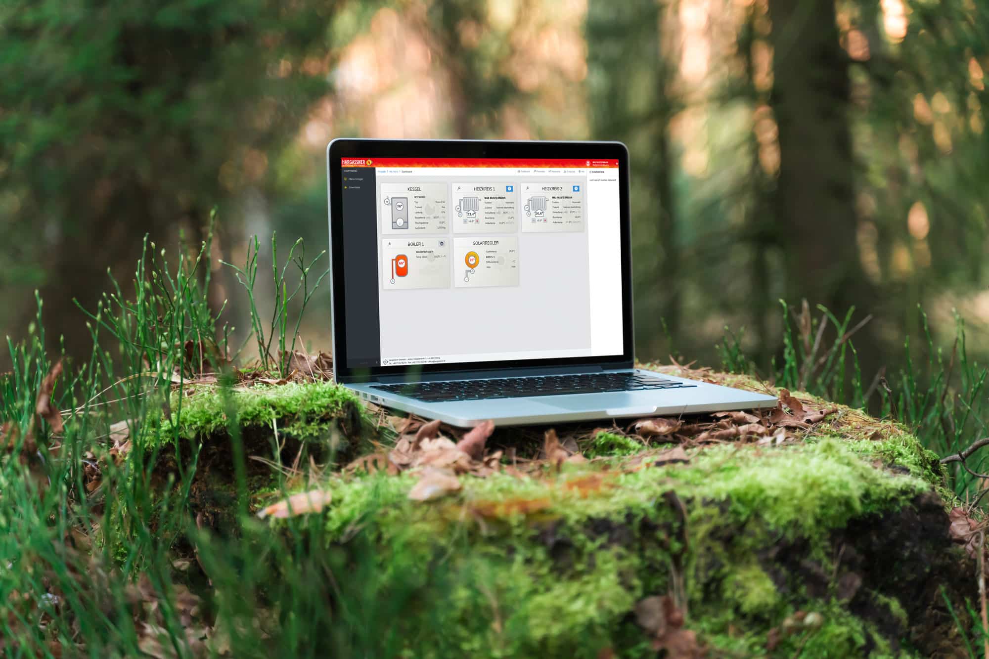 Laptop steht im Wald auf Moos und Baumstamm | Hargassner Heizungsapp