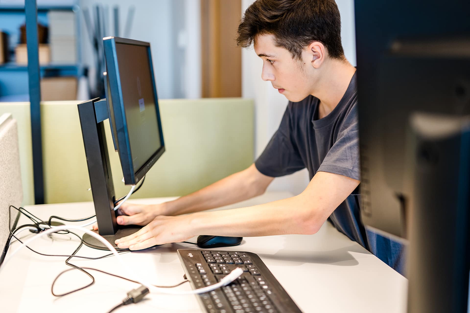 Junger Mann richtet PC am Arbeitsplatz ein | Jobs Hargassner