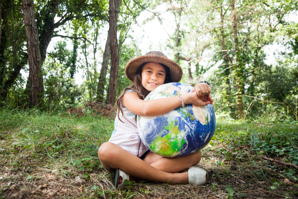 Mädchen in der Natur umarmt Weltkugel | Biomasse - Hargassner