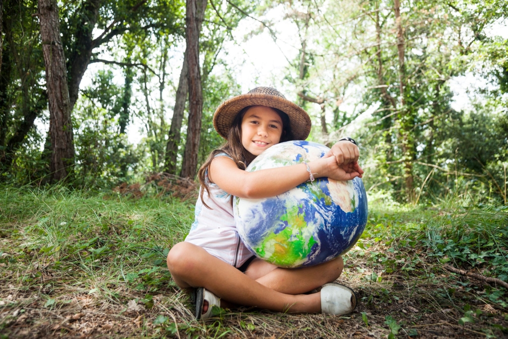 Fillette dans la nature embrassant le globe | Biomasse - Hargassner