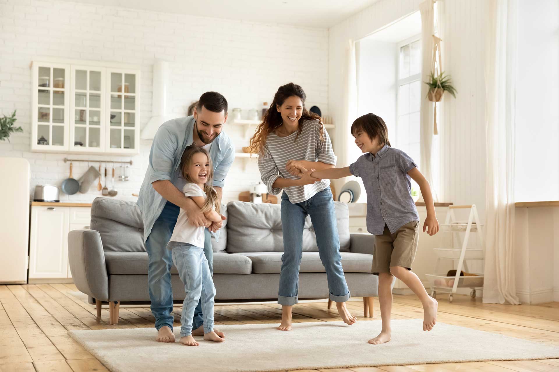 Familie mit zwei Kindern tanzt im Wohnzimmer | Hargassner
