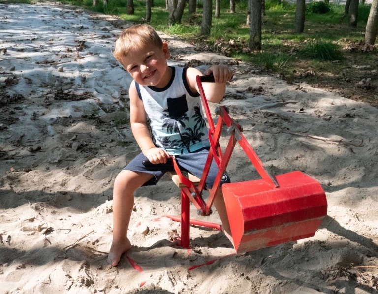 Kind spielt mit Spielzeugbagger im Sand | Kinderbetreuung | Kinderwerkstatt Hargassner