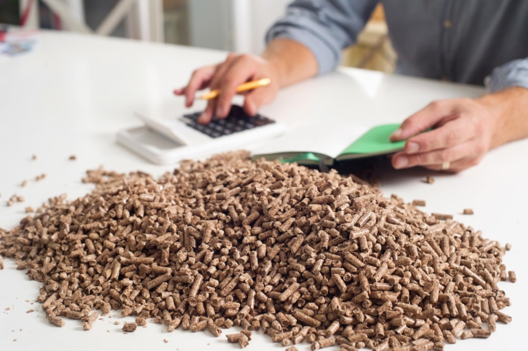 Person rechnet mit einem Taschenrechner und hat einen Stapel Pellets vor sich | Hargassner