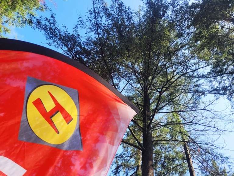 Drapeau avec le logo HARGASSNER avec un arbre et le ciel bleu en arrière plan