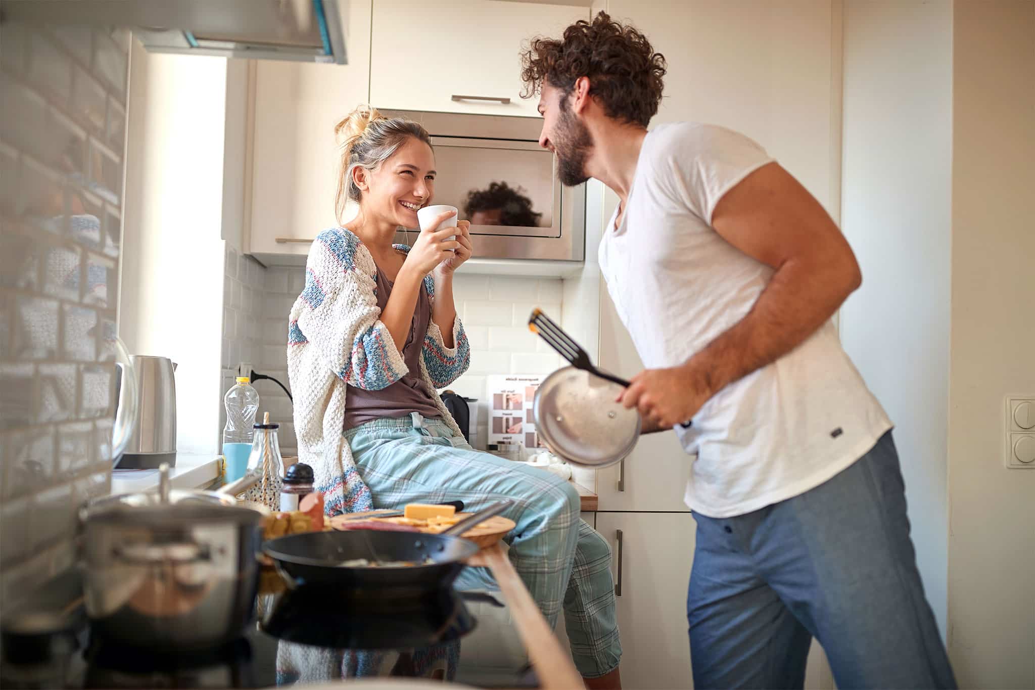 Jeune couple dans la cuisine riant et préparant un repas | Hargassner