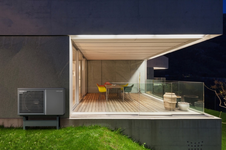 Außenansicht eines modernen Einfamilienhauses mit Wärmepumpe in der Nacht | Hargassner
