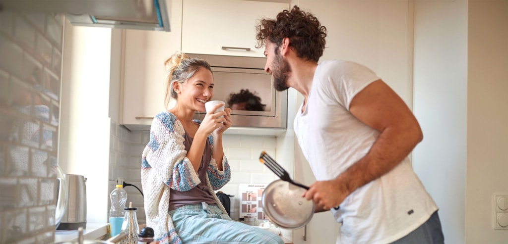 Junges Paar in der Küche lacht beim Kochen | Hargassner