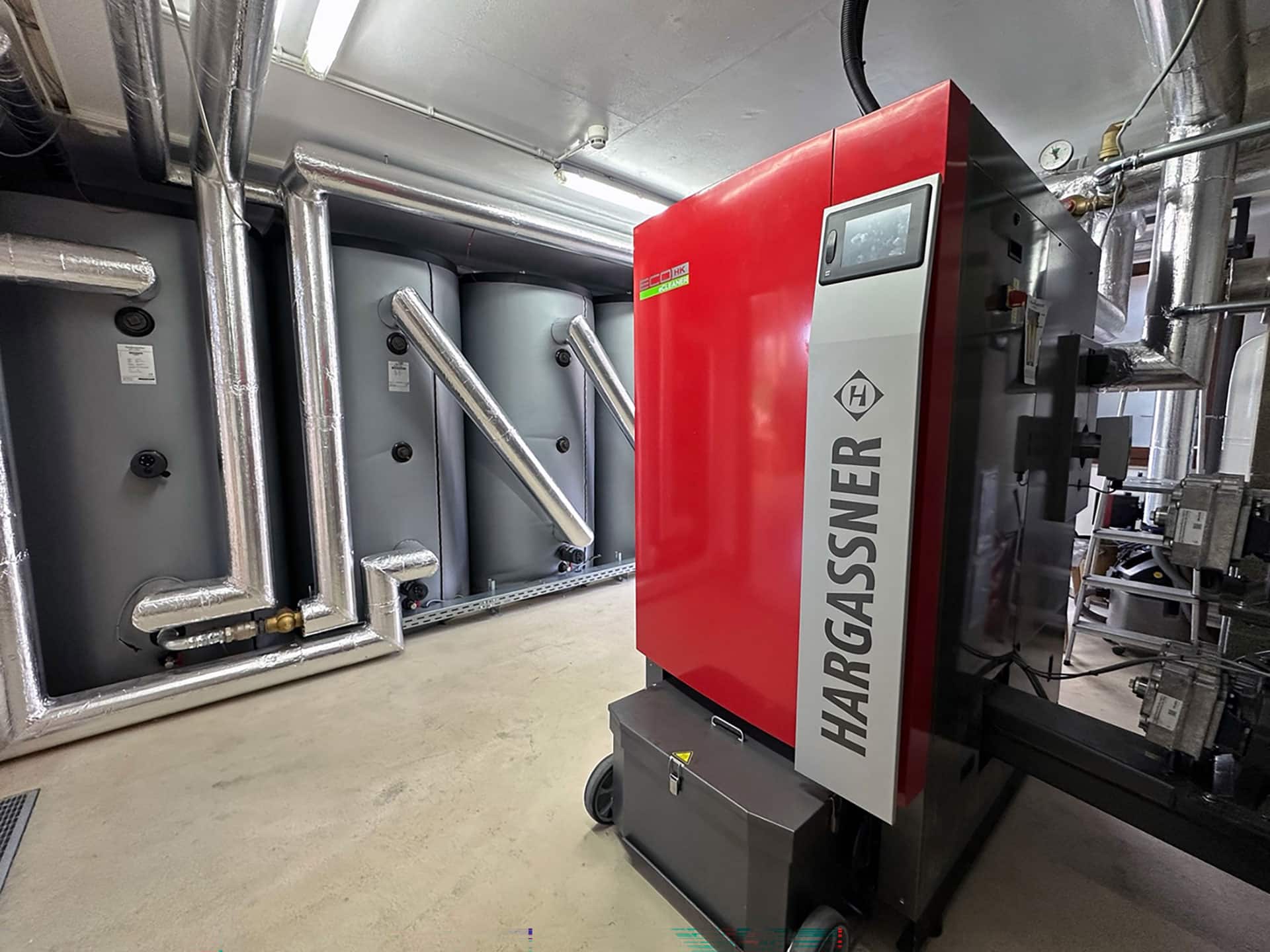 Wood chip boiler and buffer storage tank in the boiler room at the Pollmer joinery - installed by plumber Schönfelder | Reference Hargassner