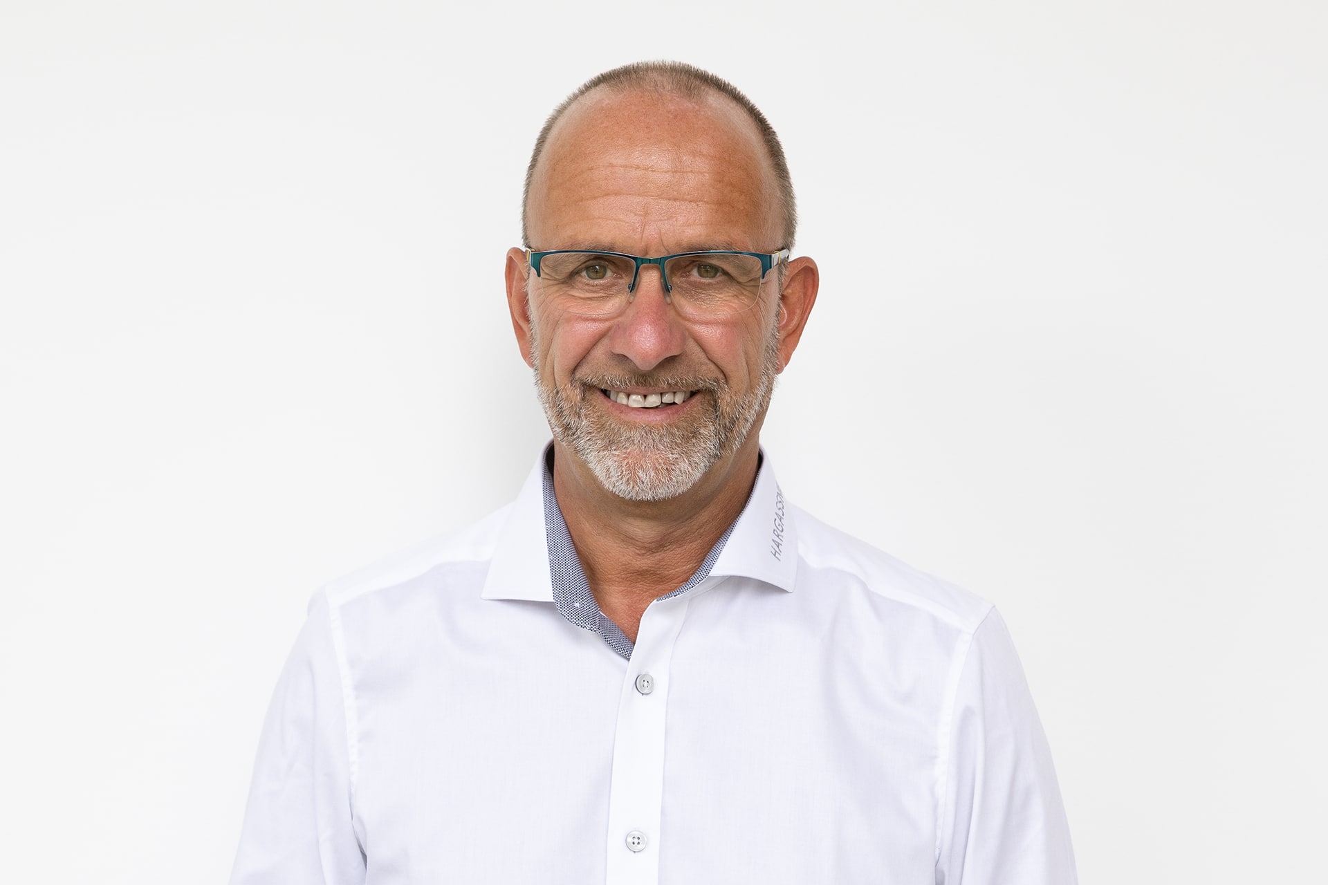 Portraitbild Markus Pangerl mit weißem Hemd vor weißer Wand