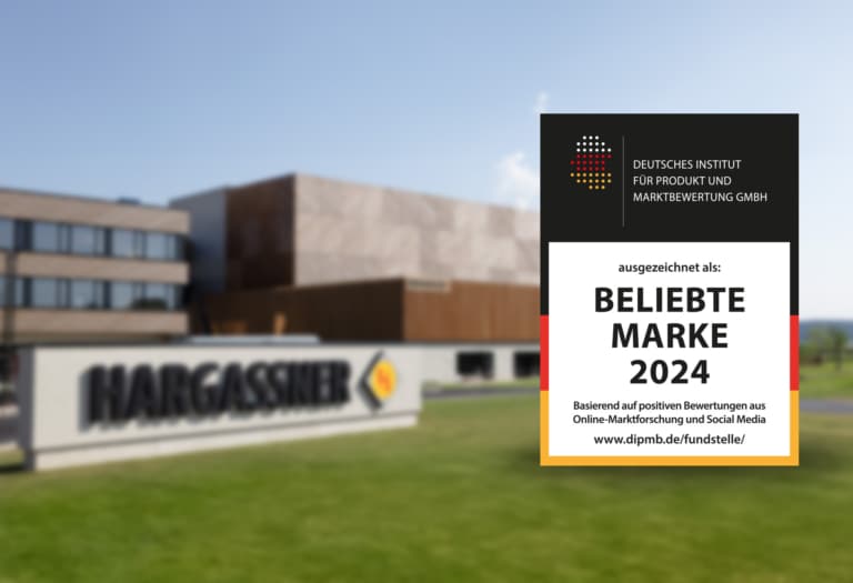 Das Gütesiegel "Beliebte Marke 2024" vor dem Hargassner-Firmengebäude mit dem neuen Parkhaus im Hintergrund.