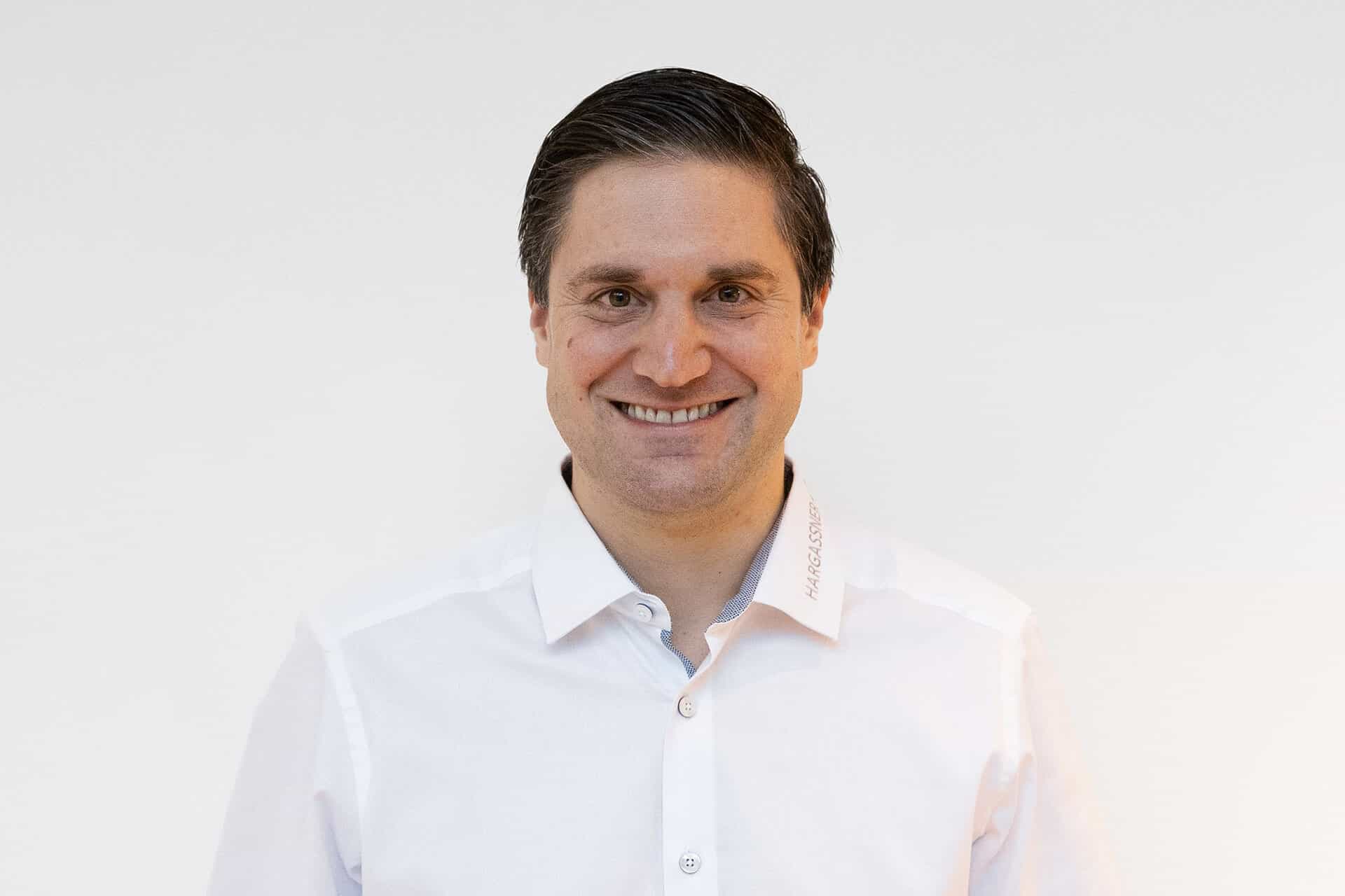 Portraitbild Christian Koch mit weißem Hemd vor weißer Wand