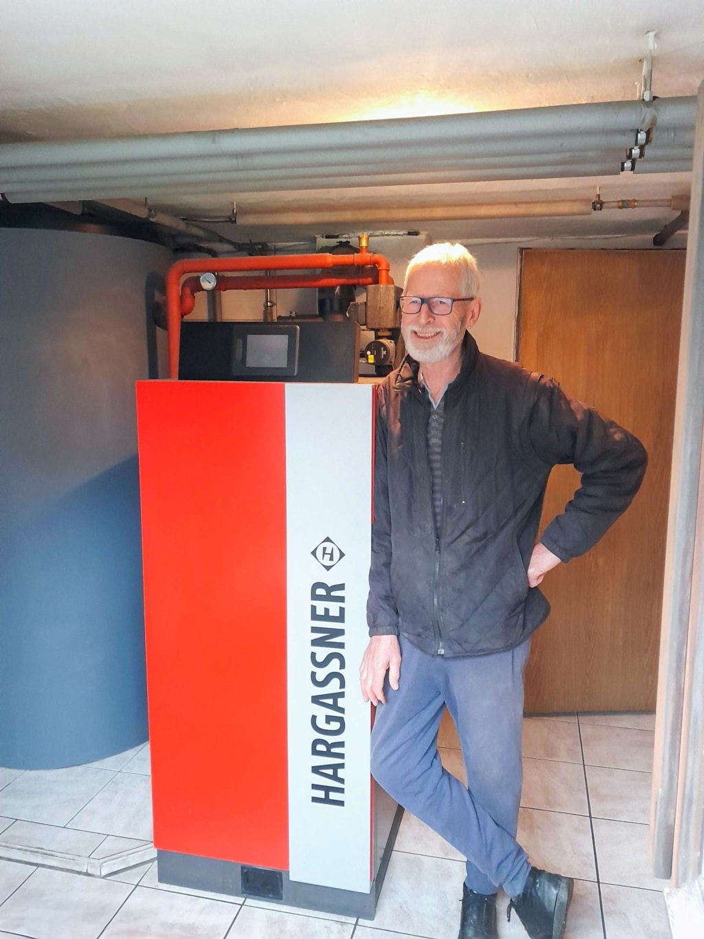Customer next to Neo-HV 20 log boiler in boiler room - Lorenz farmhouse | Hargassner reference