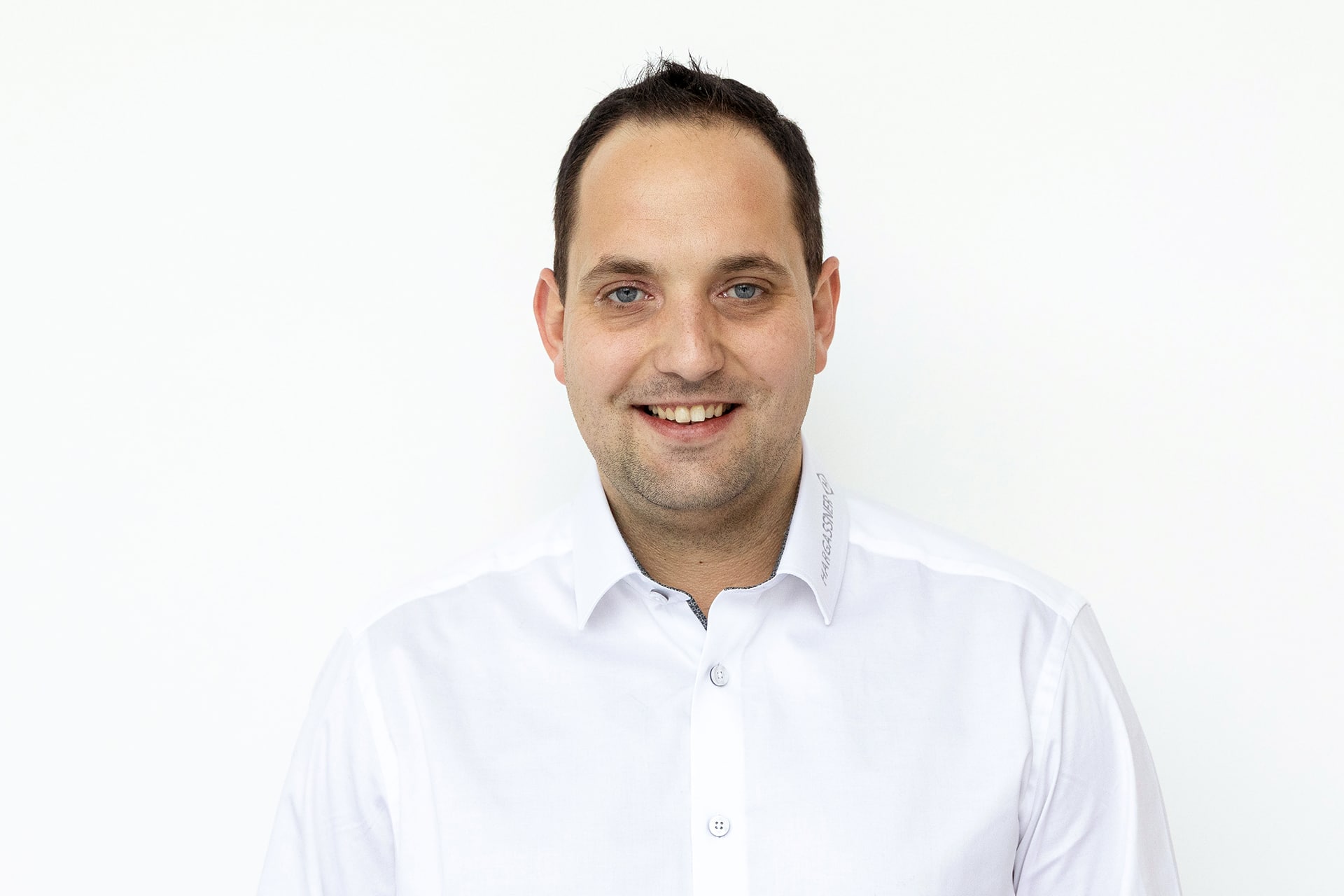 Profilbild Ansprechpartner Michael Maier in weißem Hemd vor weißer Wand.
