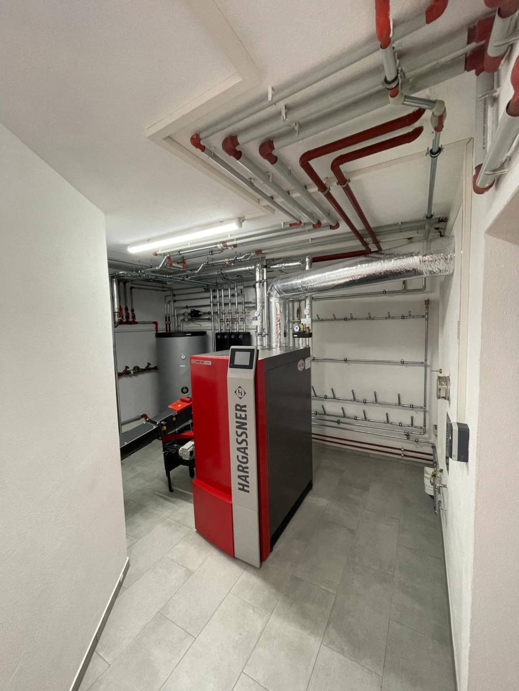 Blick in den Heizraum mit Hackgutkessel Eco-HK und Boiler von Familie Hornbacher