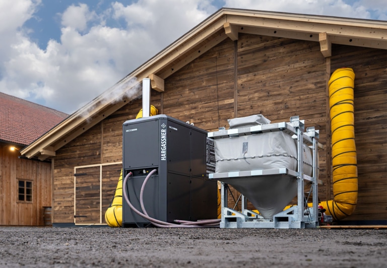 Exemple d'application d'un Eco-Airbox de Hargassner pour le chauffage d'un lieu événementiel, avec une unité de chauffage d'air chaud installée devant le bâtiment