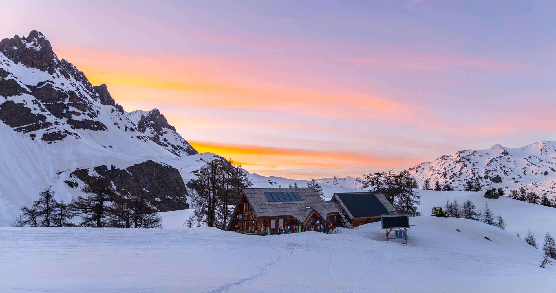 Bâtiment du refuge du chardonnet en hiver avec un couhé de soleil