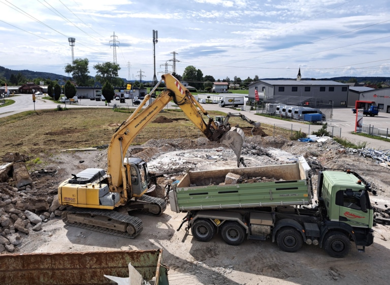 Baustart des Neubaus der Hargassner Industry Geschäftsgebäude in Regau, Bagger und LKW