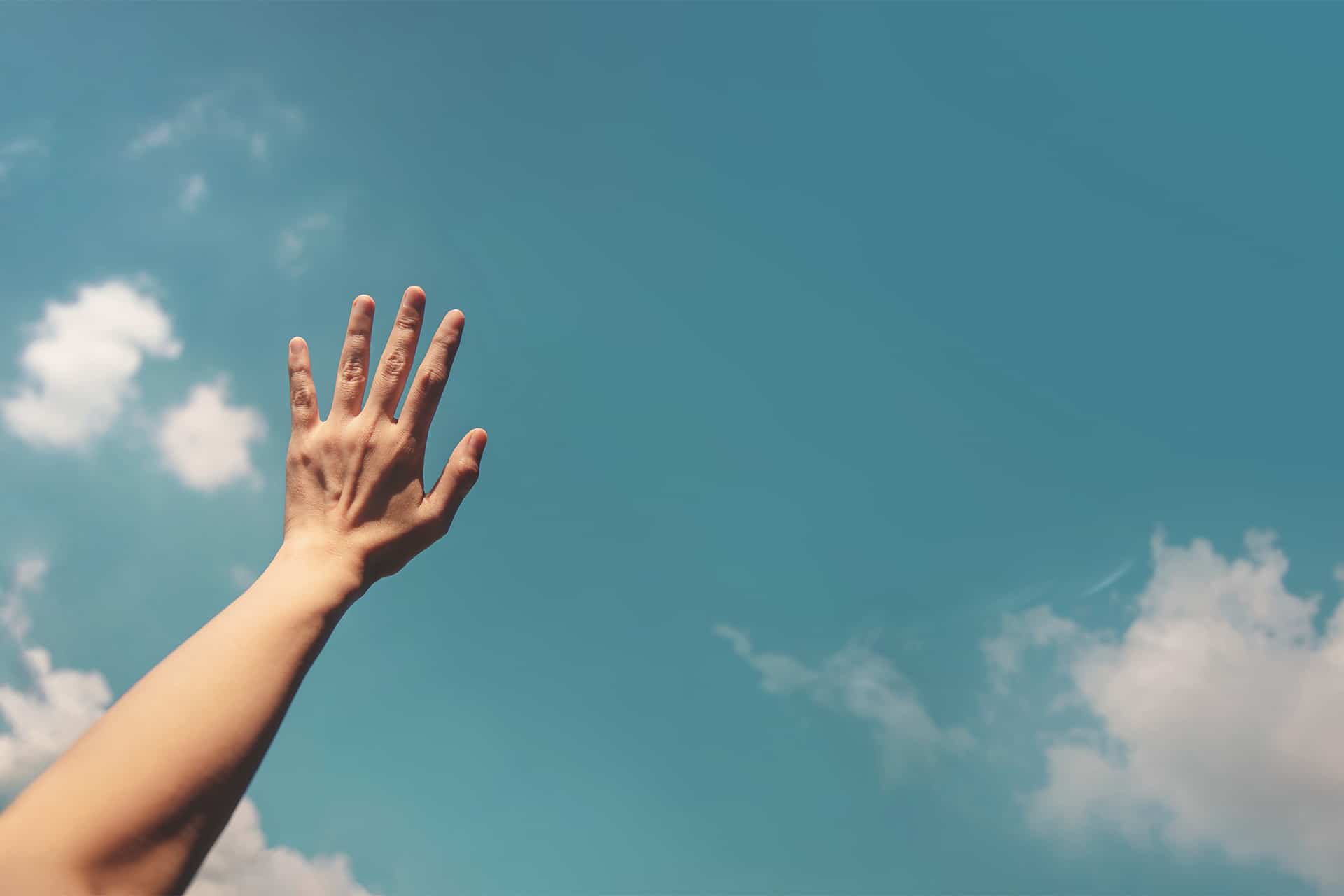 Eine Hand mit blauem Himmel und Wolken als Hintergrund