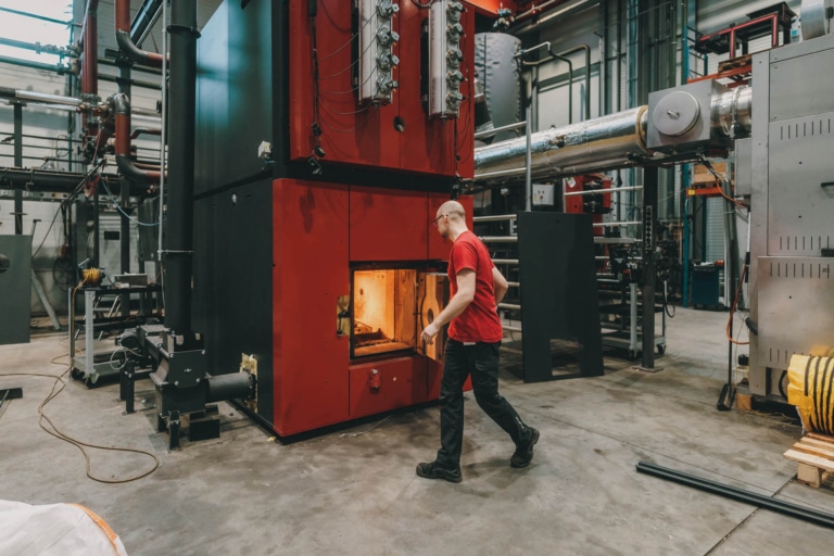 Hargassner Industrial Heating, with an employee in the foreground and the boiler door open